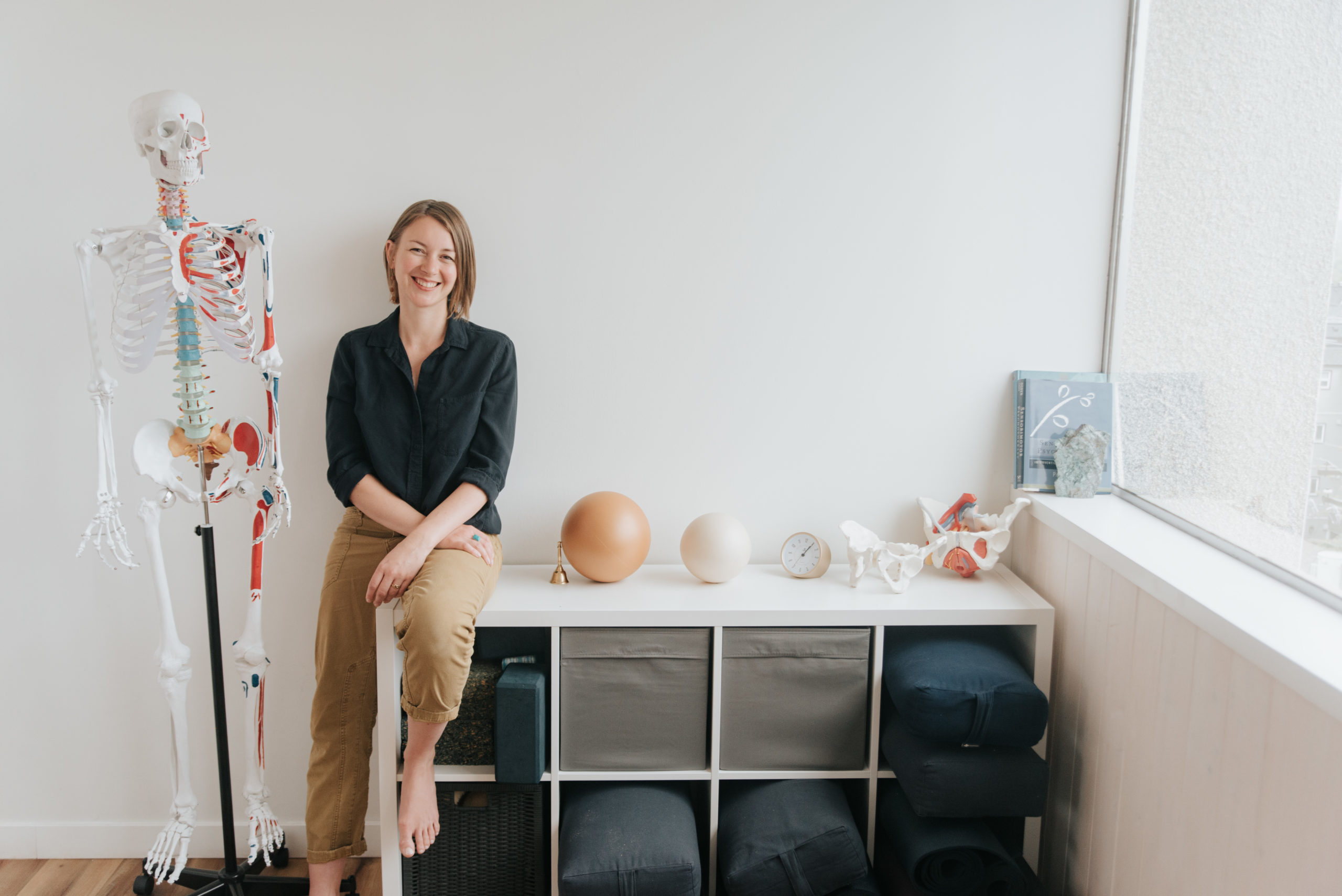 woman sitting on a small shelf with exercise equipment