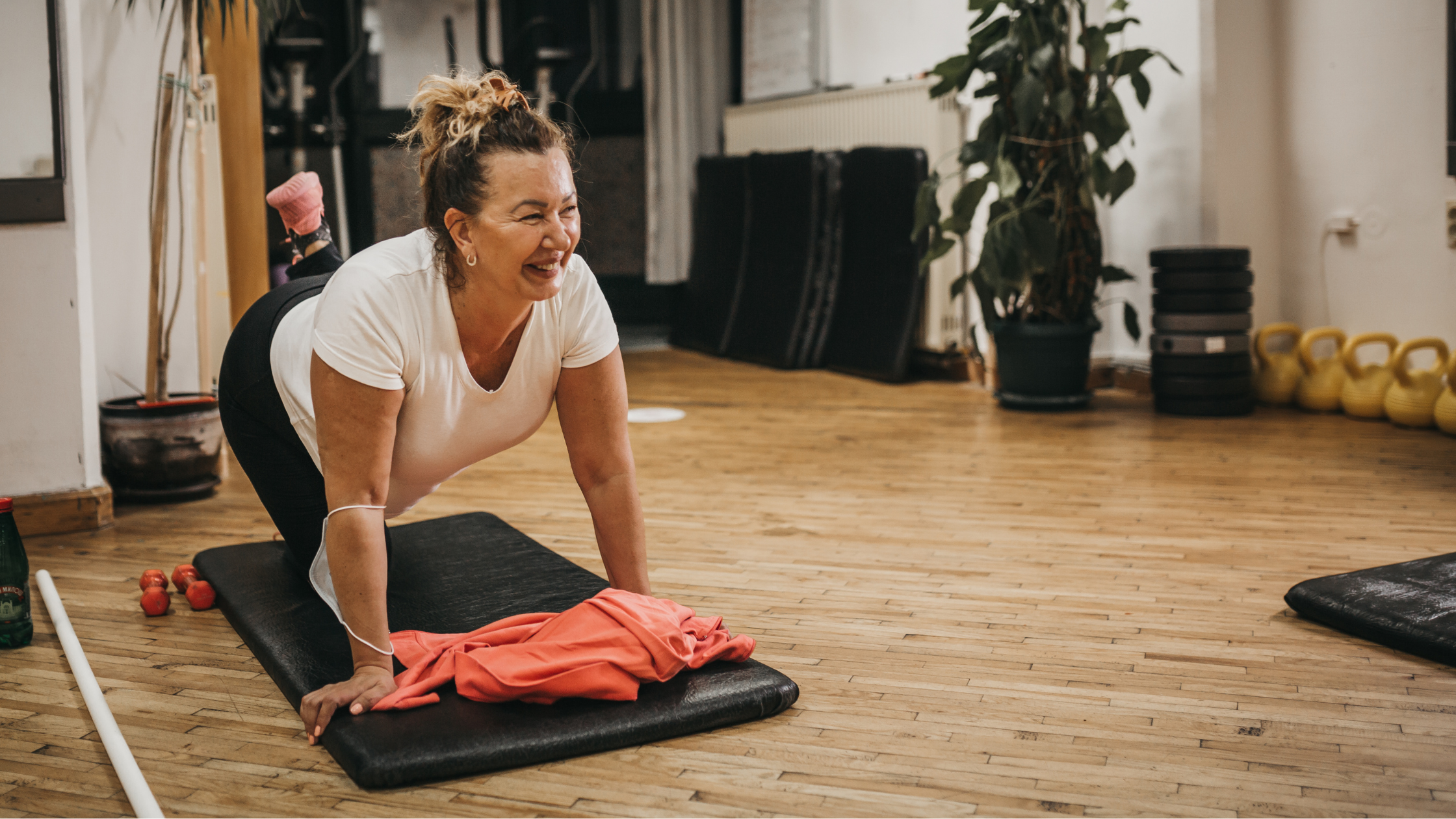 Woman smiling while doing physio exercises on a floor mat.